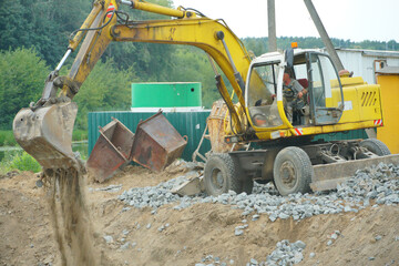 An excavator and other heavy construction equipment are working on the construction site. Construction of a new bridge across the river. Road works, laying of a new road.