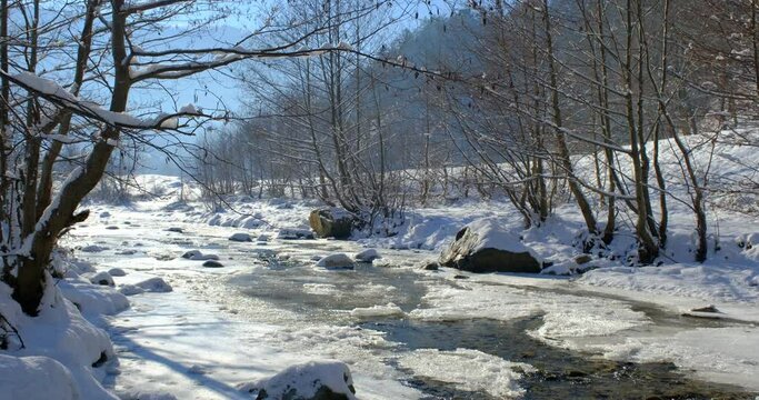 winter landscape with ice on the river and mountains in the distance, Sadu village, Sibiu, Romania
