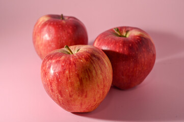 three red apples on a pink background 7