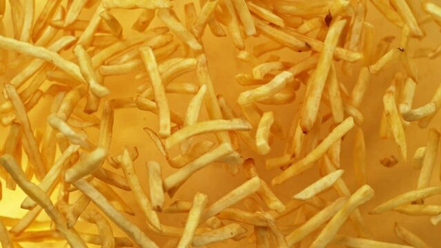 Super Slow Motion of Flying French Fries up in the Air on Golden Background. Filmed on High Speed Cinema Camera, 1000 fps.
