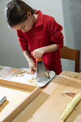 Bambina di nove anni durante la preparazione di un piatto tipico natalizio. - obrazy, fototapety, plakaty