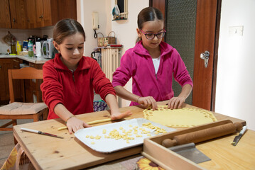 Sorelle gemelle di nove anni durante la preparazione della pasta fatta in casa.