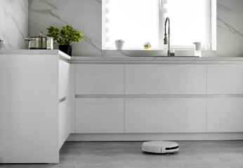 The automated robot vacuum cleaner is cleaning the floor in the kitchen. Automatic electric...