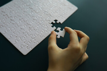 Intellectual puzzles. The puzzle is empty. The hand puts together puzzle pieces. Brain training.
