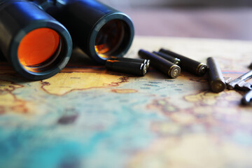 Binoculars and reflection in lenses. Map and shells background.