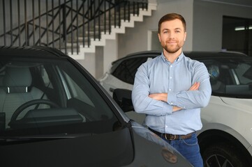 A happy man chooses a new electric car at a car dealership. The concept of buying an ecological car