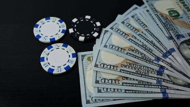 Fan of one hundred dollar bills falls on the table with lying casino fics. Concept of maximum bet, all-in, gambling, poker, risk.