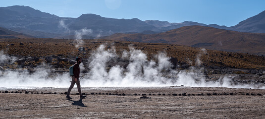 Hiker walking around El Tatio geyser field in the Andes Mountains of northern Chile