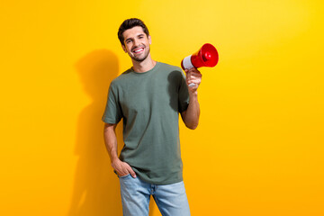 Photo of cool confident man with bristle dressed khaki t-shirt holding megaphone arm in pocket...
