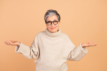Portrait of clueless aged person shrug shoulders raise arms do not know isolated on beige color...