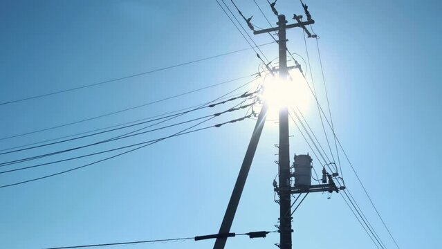 Sunlight through the electrical net of poles on a panorama of blue sky.