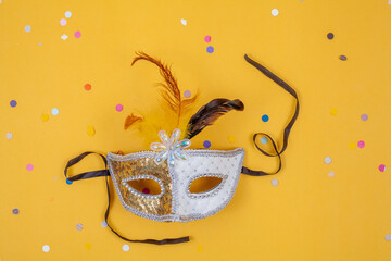 Venetian white and gold mask isolated on a yellow background