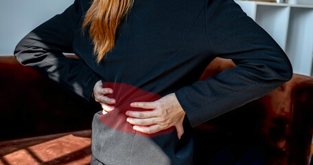 A successful businesswoman feeling waist pain and stretch herself after working hard on computer laptop for a long time in the home office, Office syndrome concept