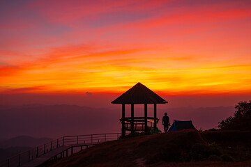 Silhouette pavilion by the hill during the dusk sky with the moon and tourists camping on the Doi Pui Co mountain in Thailand. Scenic landscape, Hiking trails, and camping in Northern Thailand
