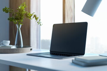 Modern designer desktop with mock up laptop, various objects and window with city view in the background. 3D Rendering.
