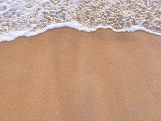 sunny Small, Soft wave on sand beach, text copy space for banners, cards. Close up top view of sea blue waves break on sand. photo was shot in evening at sunset - obrazy, fototapety, plakaty