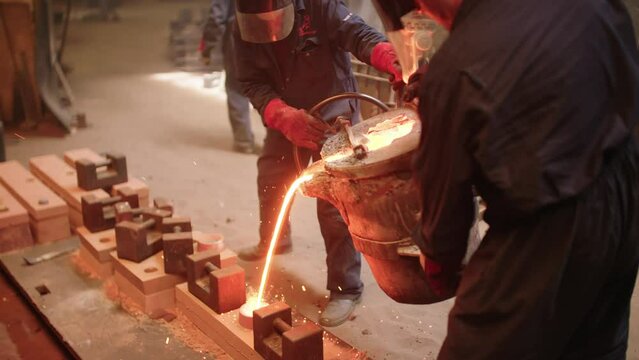 4K Two men Pour Molten Metal into mold