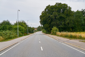 Fototapeta na wymiar Empty road or street with sidewalk in rural Sweden