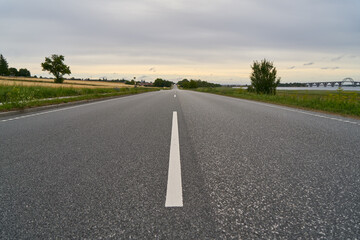 Asphalt street with two lanes and road markings in rural countryside - obrazy, fototapety, plakaty