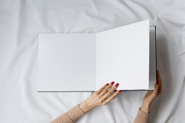 Beautifully manicured hands holding open blank gray book on white background