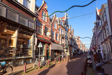 Sunny Amsterdam street with typical Dutch houses at gold hour, Holland, Netherlands.