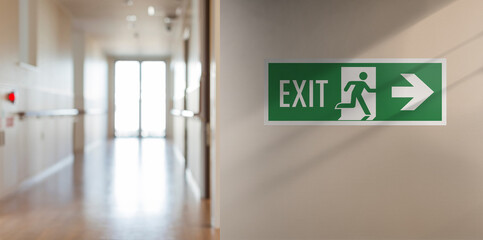 Emergency fire exit sign in the corridor of the school. Arrow on the right, blurred background with...