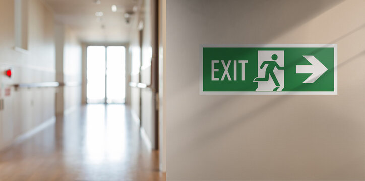 Emergency fire exit sign in the corridor of the school. Arrow on the right, blurred background with copy space for text and messages.