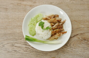 slice grilled chicken topping white sesame with Teriyaki Japanese sauce on rice in plate with cucumber and spring onion