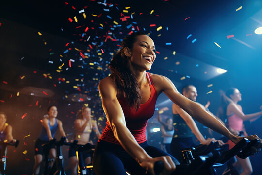 Sporty woman in activewear training on bike during spinning class at gym. Cycling class in fitness club, group of fit people spinning on cardio machines.