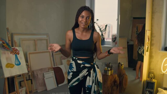 Medium POV UGC of gen Z young pretty lady with box braids and in fitness suit introducing herself and explaining dance moves techniques moving for camera at home