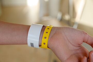 close-up of yellow plastic bracelet on the girl arm of child clinic patient, check tape with entry number on hand of teenager girl, event ticket concept - obrazy, fototapety, plakaty