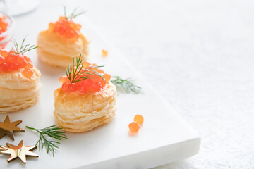 Salmon red caviar toast. Christmas canape or toast with red caviar on white plate on light background. Idea to xmas snack. Gourmet food. Texture of caviar. Seafood.