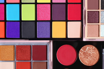Various colorful eyeshadow palettes on bright pink background. Flat lay.