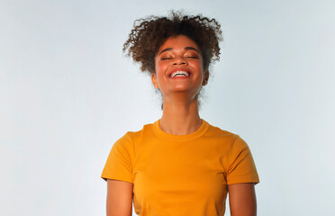 Overjoyed african american woman in bright yellow tshirt with curly hair laughing looking into...