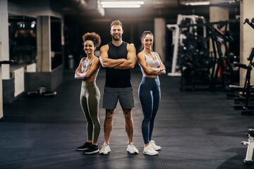 Portrait of muscular sportspeople in shape posing in a gym while smiling at the camera.