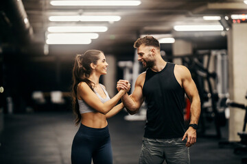 A sporty couple is giving pond hug in a gym.