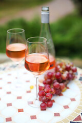 Two glasses and bottle of rose wine in autumn vineyard on marble table
