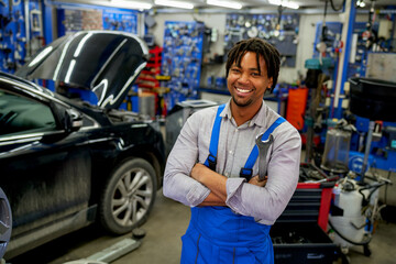An African-American mechanic confidently posing with tools in hand in his workshop.