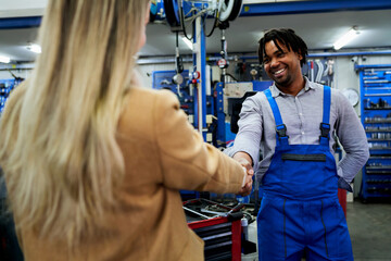 In the mechanic's haven, a close-up captures a handshake between an African-American mechanic and a...