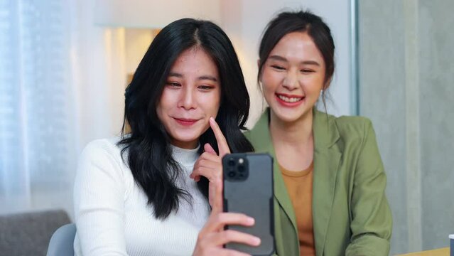 taking selfie photo. Two happy smilling asian young women take selfie on mobile phone at home office