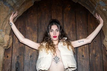pretty woman with tattoos standing against a wooden door