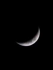 This is a picture of the crescent moon. The surface of the moon is visible.
