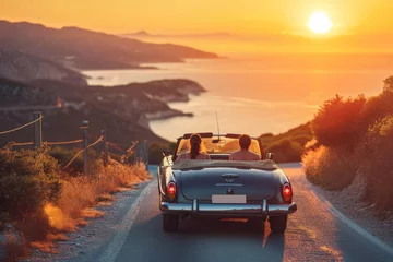 Fotobehang friends in convertible on a road trip in mountains and sea view on the sunset © Наталья Добровольска