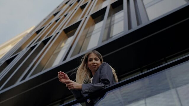 A woman with long hair looks at the city from the balcony of the hotel. Urban people, cityscape. Portrait of nice mixed-race asian young beautiful woman. Shot of a confident young woman.