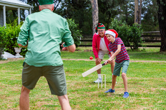 Christmastime backyard cricket game with boy hitting ball - Powered by Adobe