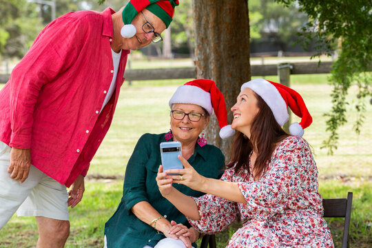 Family looking at photos on phone together while sitting in shade at Christmas