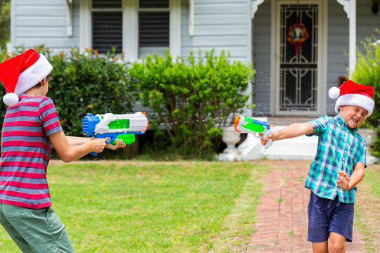 Brothers pointing blaster pistols in Christmastime water fight