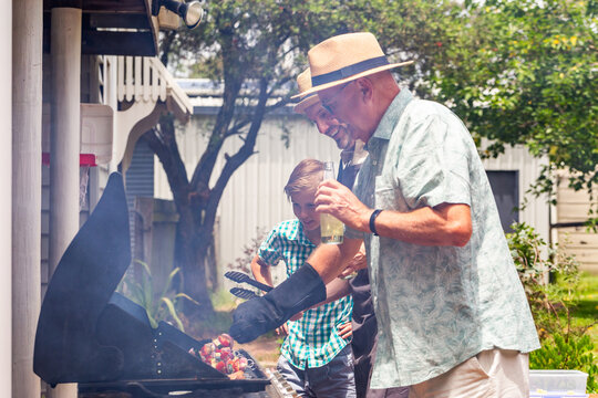 Generations of men cooking barbeque together at family gathering