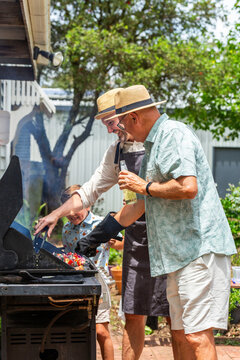 Generations of men cooking barbeque together at family gathering