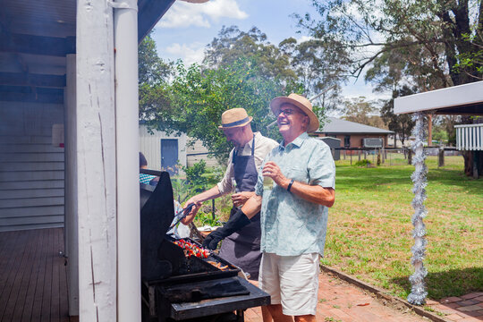 men laughing around barbeque in backyard at summertime family gathering